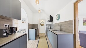 Una cocina compacta con electrodomésticos modernos, horno integrado y un lavamanos.