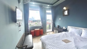 Een hotelkamer met een bed, een bureau, een stoel, een bank en uitzicht.