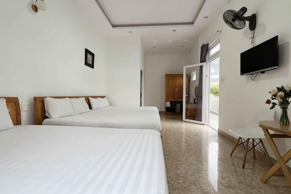Habitación de hotel con dos camas, televisión, escritorio y zona de comedor.