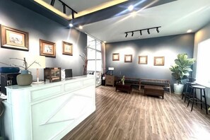 A reception area with a counter, seating, and framed pictures on the walls. - Hung Nguyen Valley Dalat Hotel (Dalat)