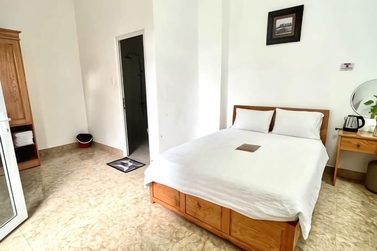 A bedroom with a wooden bed, a bedside table with a mirror, and a wardrobe.