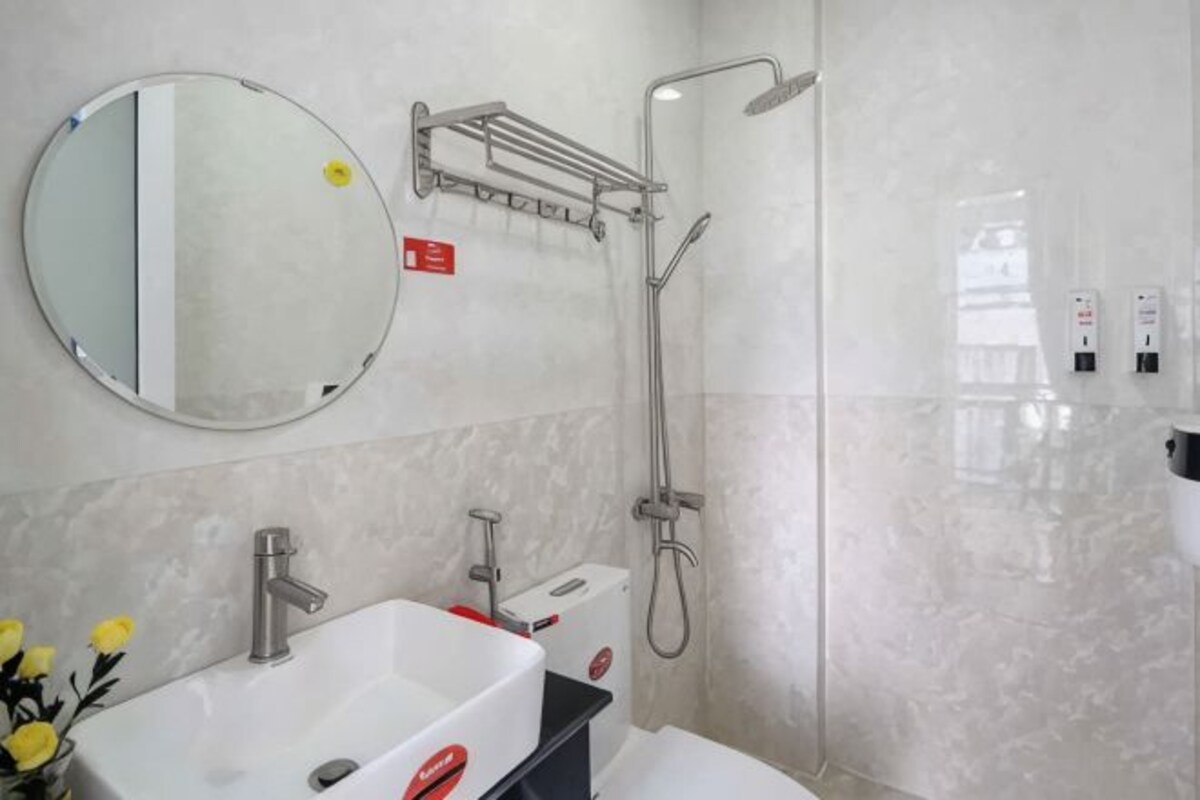 Un baño moderno con lavamanos, espejo y ducha blancos.