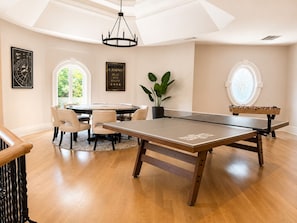 A spacious room with a foosball table, a round table with chairs, and a large window. - 5M Luxury Estate Experience/Atlanta Near Buckhead (Sandy Springs)