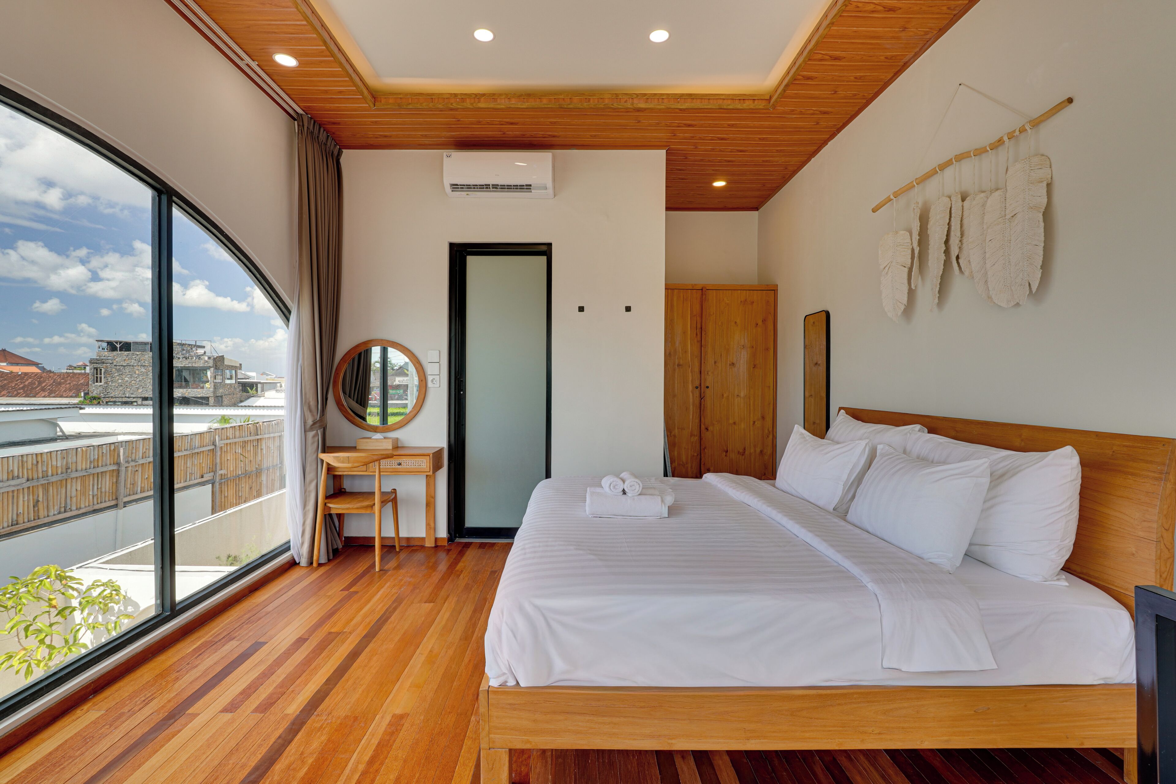 Une chambre d’hôtel avec une grande fenêtre, un lit, un bureau et une armoire.