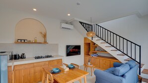 Una cocina moderna con comedor, una escalera y una sala de estar con sofá.