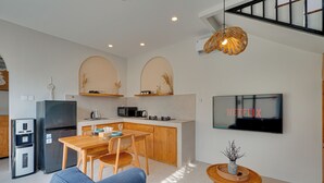Una cocina moderna con comedor, sofá y televisor montado en la pared.