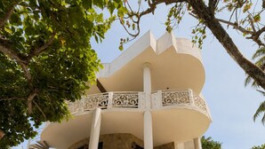 Un edificio de varios pisos con balcones, piso de piedra y barandillas decorativas.