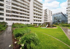 Een modern appartementencomplex met meerdere balkons, een speeltuin en verzorgde groene ruimtes.