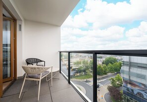 Een balkon met uitzicht op een stadsgezicht, een stoel en een tafel.