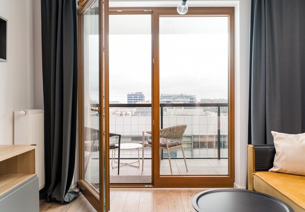 Ein modernes Wohnzimmer mit einer Schiebeglastür, die auf einen Balkon im Freien führt.