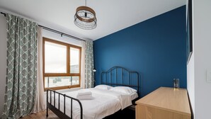 Ett sovrum med en säng, ett skrivbord, ett fönster och en hängande lampa.