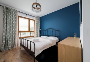 Ein Schlafzimmer mit einem Bett, einem Schreibtisch, einem Fenster und einer Pendelleuchte.
