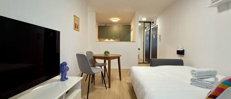 Une chambre d’hôtel comprenant un lit, une télévision, un bureau avec des chaises, une petite table et une armoire.