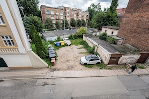 Ein Wohngebiet mit mehreren Gebäuden, parkenden Autos und einem unbefestigten Grundstück.