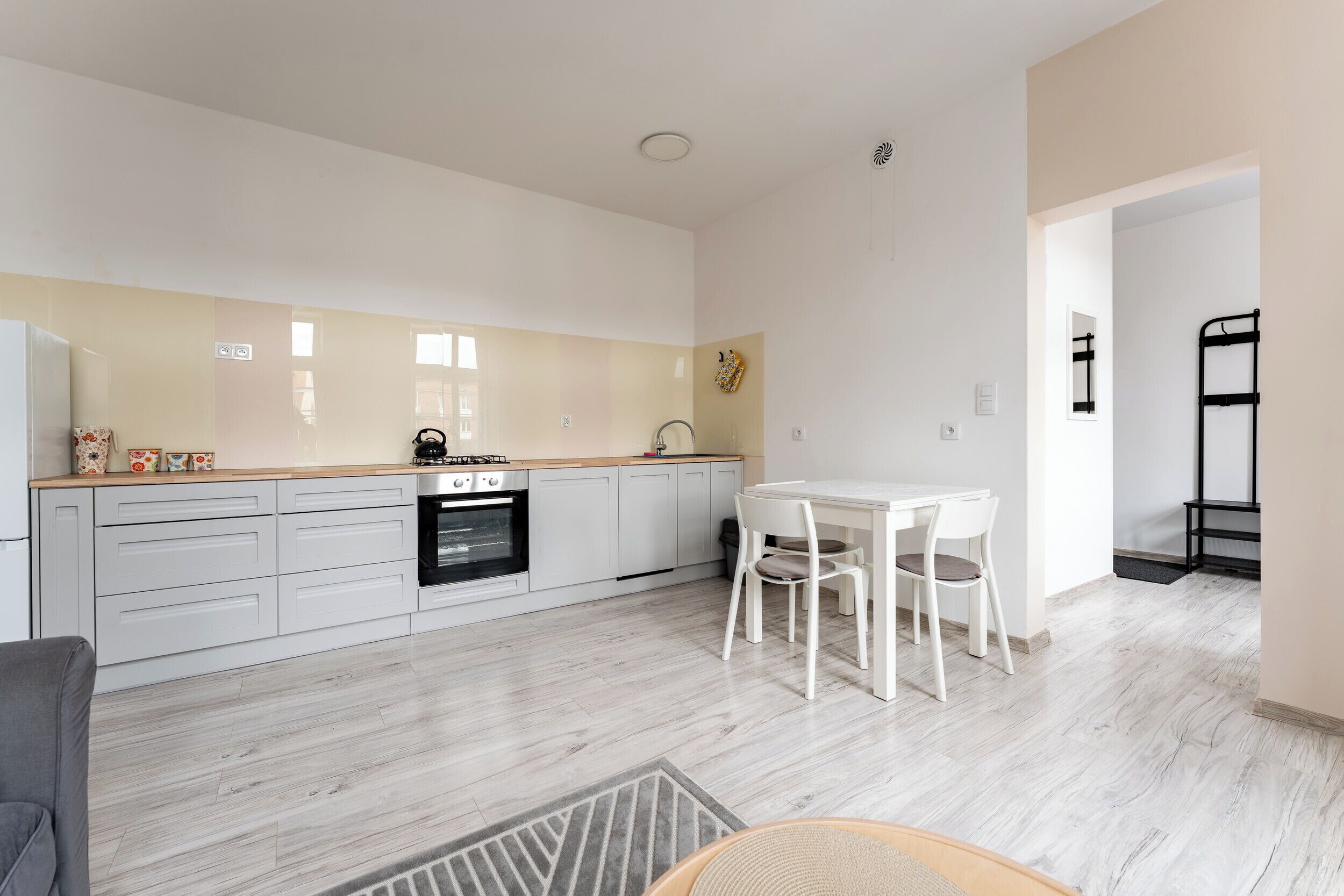 Une cuisine moderne avec des meubles blancs, une cuisinière à gaz et un coin repas comprenant une table et des chaises blanches.