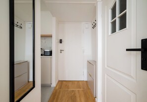 A hallway with a wooden floor leading to a kitchen area with a refrigerator and a countertop. - Rondo ONZ Cozy Stay Apartment (Warszawa)