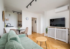 A modern living room with a sofa, a dining table, and a TV. - Rondo ONZ Cozy Stay Apartment (Warszawa)