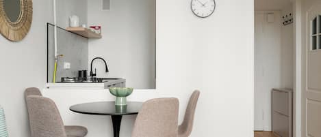 A modern kitchen with a round table, two chairs, a clock, and a mirror.