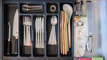 A drawer with utensils, including forks, knives, spoons, and a bottle opener.