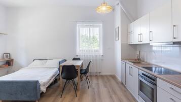Une chambre compacte et moderne, équipée d’un lit, d’une table à manger et d’un coin cuisine.