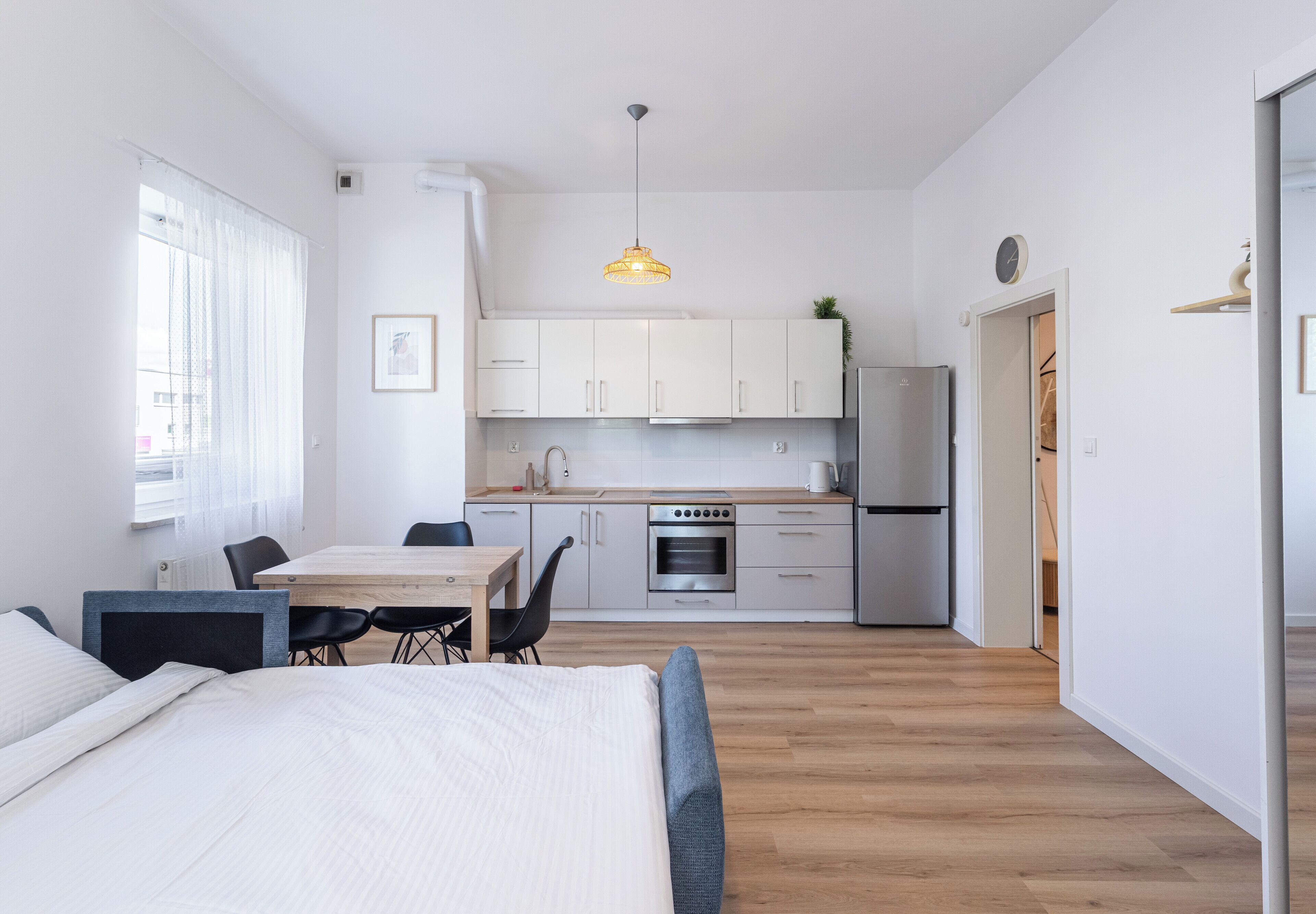 Eine kompakte, moderne Wohnung mit Küchenzeile, Essbereich und Schlafzimmer.