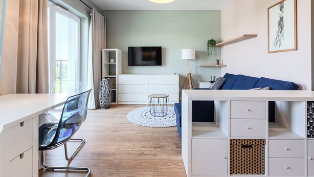 Ein modernes Wohnzimmer mit Flachbildfernseher, einer Couch, einem Esstisch und einer Küchenzeile.