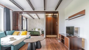 Una habitación de hotel moderna con sofá, cama, televisor y piso de madera.