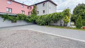 Un barrio residencial con dos casas, una rosa y otra blanca, con entrada pavimentada y zonas verdes.