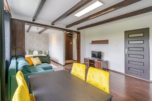 A modern living room with a sofa, a dining table, and a TV.