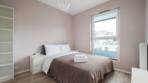 Ein Schlafzimmer mit Bett, Nachttischen, einem Kleiderschrank, einem Fenster mit Rollläden und einer Heizung.