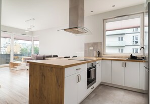 A modern kitchen with a wooden island, built-in oven, and a large window. - Bielany Boutique Apartment (Warszawa)