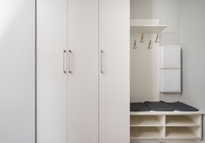 Ein weißer Kleiderschrank mit zwei Türen und einem Regal darüber.