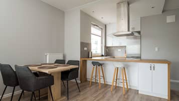 A modern kitchen with a central island, bar stools, and a dining table with chairs.