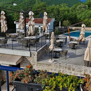 Una terraza al aire libre con mesas y sillas, una piscina y una zona de recepción.