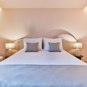Una habitación de hotel con una cama grande, dos lámparas de noche y un cabecero.