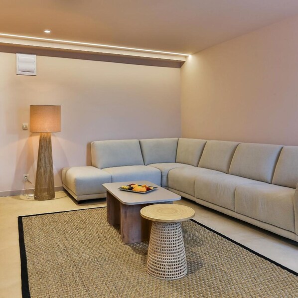 Una sala de estar moderna con un sofá, una mesa de centro, una lámpara y una mesita redonda.