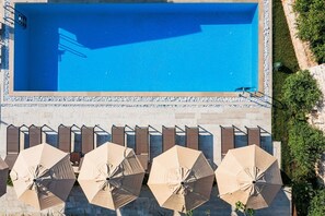 Une piscine avec une terrasse carrelée et des parasols.