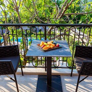 Une table avec un assortiment de fruits, placée sur un balcon doté de rampes et de chaises en métal.
