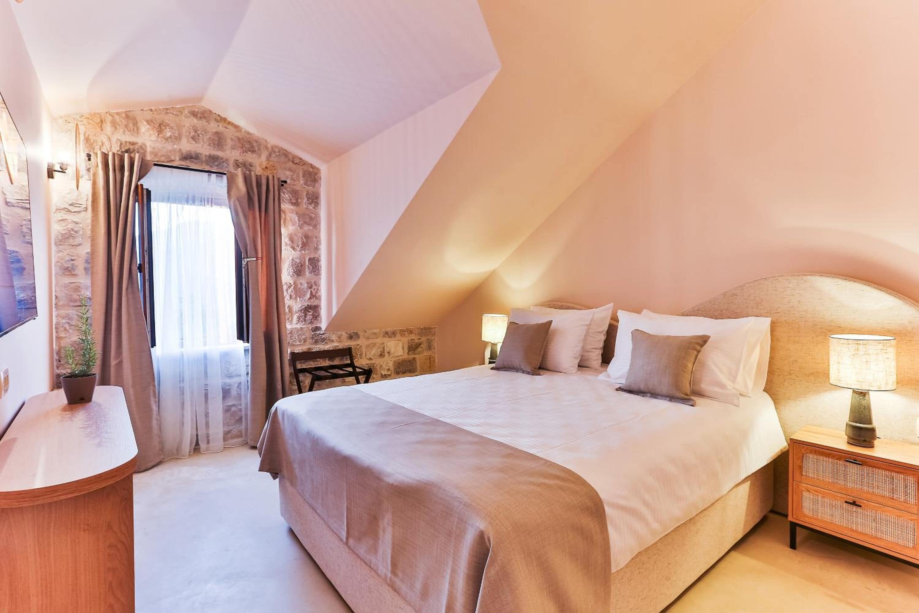 A bedroom with a bed, bedside tables, a lamp, a chair, and a window with curtains.