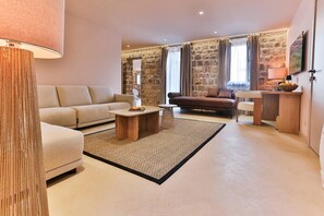 A living room with a sofa, a coffee table, and a stone wall. - Boutique Hotel Ruzmarin SPA & Garden (Budva)