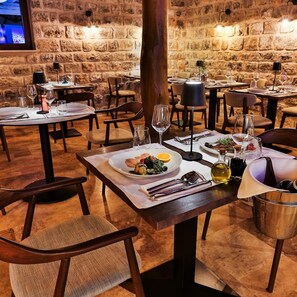 A restaurant with stone walls, wooden tables, and chairs. - Boutique Hotel Ruzmarin SPA & Garden (Budva)