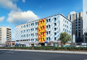 A multi-story building with a distinctive geometric facade, a central vertical feature with a yellow and red pattern, and a clear sky in the background. - Crystal Hotel Beijing Chongwenmen (Beijing)