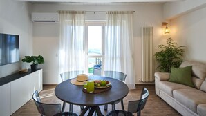 A modern living room with a round dining table, a sofa, and a large window with curtains. - Villa Esther, 7 bedrooms, pool, A/C, EV charger, pet friendly, Marche (Fermignano)