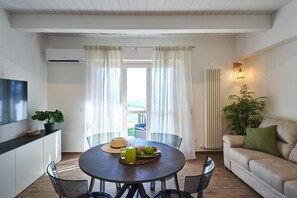A modern living room with a round dining table, a sofa, and a large window with curtains. - Villa Esther, 7 bedrooms, pool, A/C, EV charger, pet friendly, Marche (Fermignano)