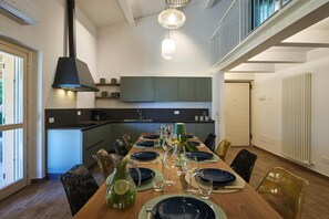 A modern dining area with a long table set for a meal, a kitchen in the background, and a staircase leading to an upper level. - Villa Esther, 7 bedrooms, pool, A/C, EV charger, pet friendly, Marche (Fermignano)