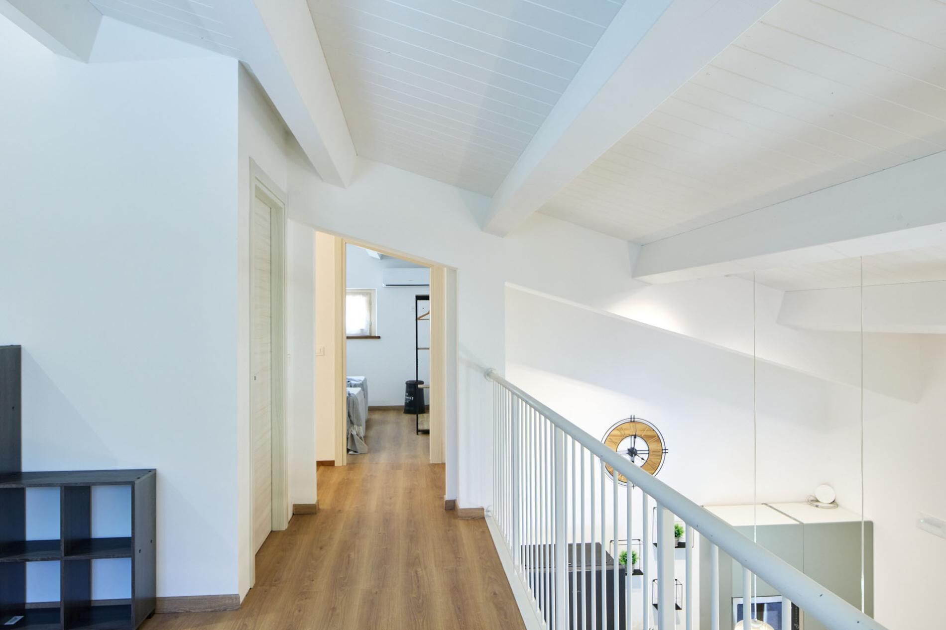 A spacious interior with a wooden floor, white walls, and a staircase with a metal railing.