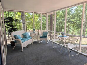 Un espace extérieur abrité, aménagé avec des meubles en osier, une table et des chaises.
