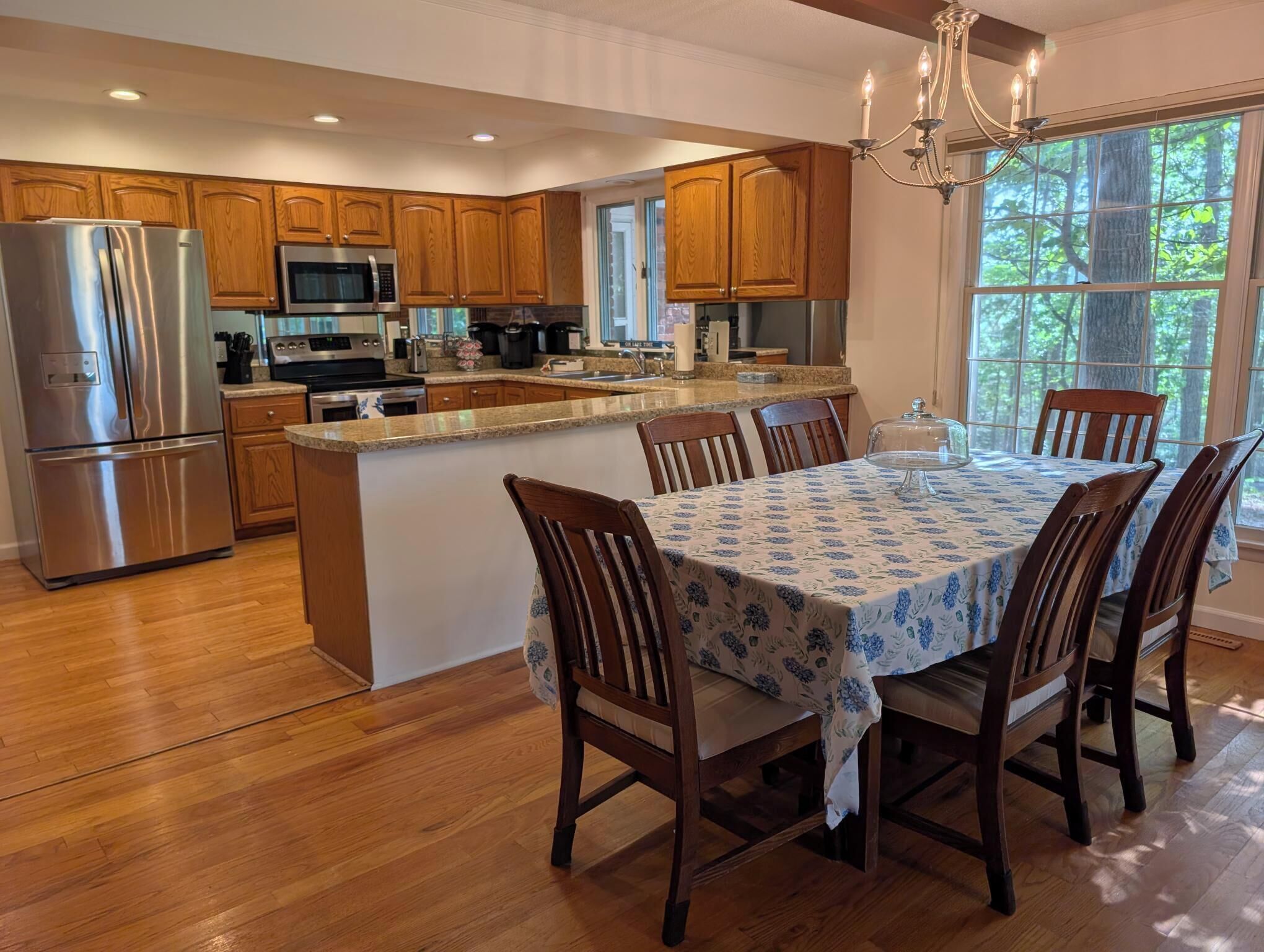 A modern kitchen with wooden cabinets, stainless steel appliances, and a dining area with a table and chairs.