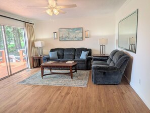 A living room with a dark grey sofa set, a wooden coffee table, and a painting of sailboats on the wall.