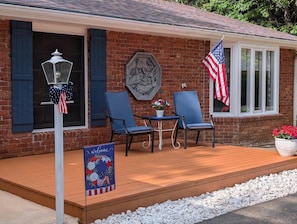 A brick building with a porch, two chairs, a table, an American flag, a welcome sign, and a decorative lantern. - Beautiful & Spacious 3 bedroom/3 bath home with stunning views of Norfolk Lake (mountain home)
